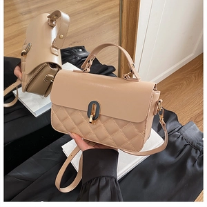 Macro detail of beige quilted handbag with black and gold twist lock and mirror reflection