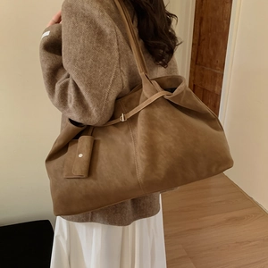 Close-up of a large vintage brown suede tote bag with metal buckle worn by a model