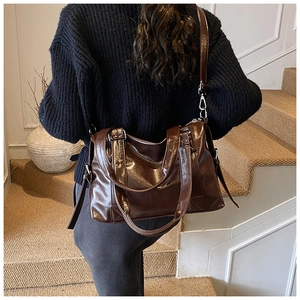 Deep brown glossy leather tote bag shown with shoulder strap on a model background