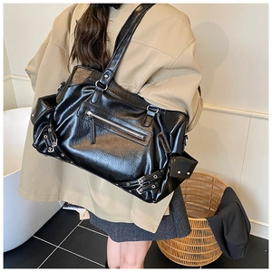 Detail of vintage black tote with silver metal buckles and punk style leather straps