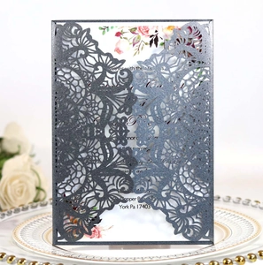 Macro detail of laser-cut wedding invitation in dark charcoal on an elegant dinner plate