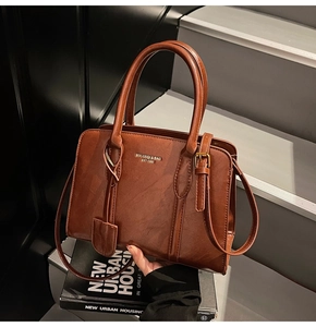 Detailed close-up of a brown vintage tote bag with gold lettering on a concrete stair