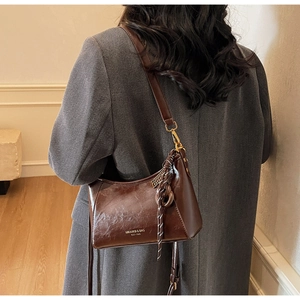 Dettaglio della borsa a spalla vintage in pelle marrone con decorazione in corda intrecciata