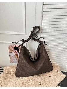 Detail of vintage brown tote bag featuring pleated shoulder straps and side drawstring accents