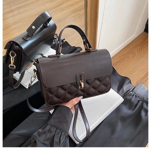 Detail of dark brown leather handbag with diamond quilting and gold oval twist lock