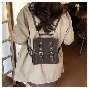 Detail of vintage dark brown mini backpack with gold buckles and cream stitching