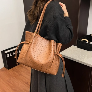 Detail of brown ostrich texture tote bag with side drawstring and adjustable strap