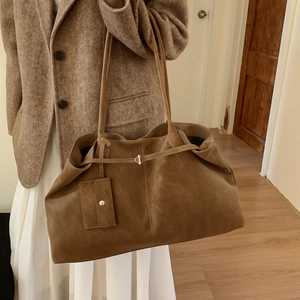 Detail of a brown leather tote bag with silver buckle and matching coin purse charm