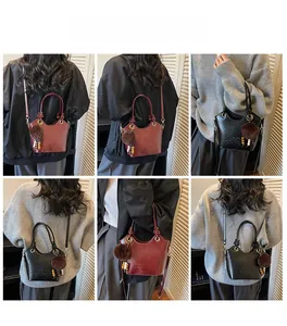 Detail view of mini bucket bags in reddish-brown and black with plush ball pendant charm