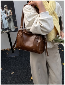 Close-up of brown faux leather tote with reinforced cross stitching and side zipper detail