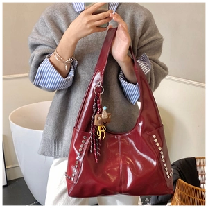 Détails du sac cabas en cuir verni rouge avec rivets argentés et charme d'ours