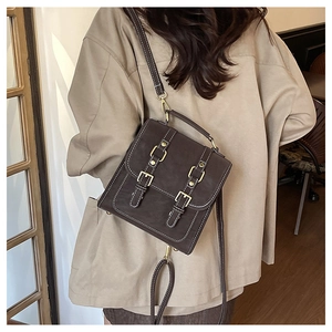 Rear view of model wearing a vintage dark brown leather crossbody bag with white stitching
