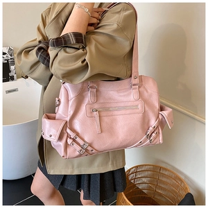 Detail of pink pebbled leather tote with side buckle pocket and metal hardware on handle