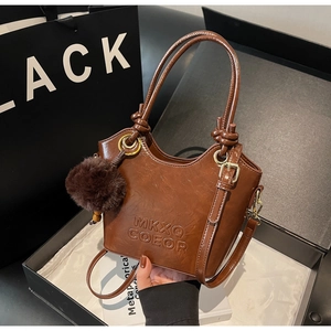 Detail of vintage brown bucket bag with glossy texture and plush ball charm accessory