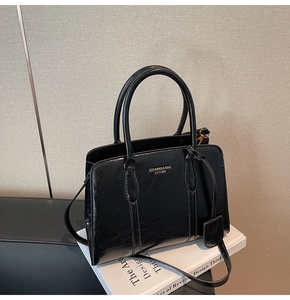 Detail of vintage texture black leather handbag with golden logo on white art book