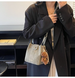 Detail of sage green bucket bag featuring contrast stitching and cute plush bear charm