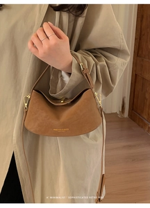 Detail of caramel leather handbag featuring gold embossed logo and elegant strap hardware