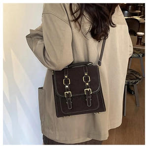Detailed view of coffee brown suede crossbody bag with decorative buckles and cream stitching