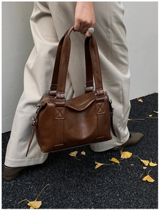 Close-up of vintage brown tote bag with double handles and polished leather texture