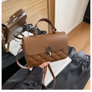 Detailed macro of brown quilted faux leather handbag with golden oval clasp and stitching