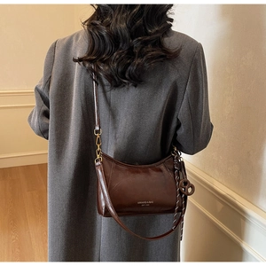Detail view of the vintage leather shoulder bag with gold hardware and brand logo