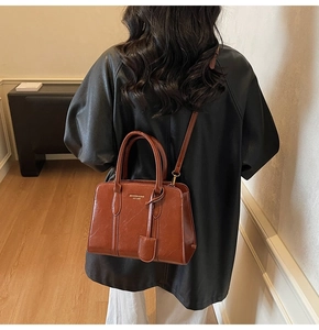 Detail of vintage brown glossy leather tote bag showing gold embossed brand text and strap