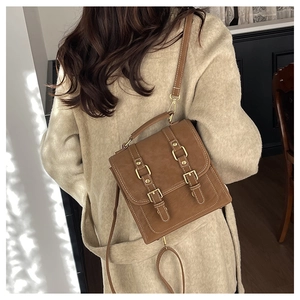 Brown vintage messenger backpack in matte finish shown on model in beige coat