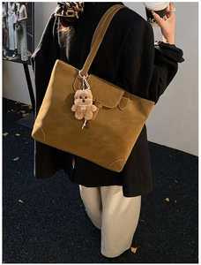 Brown tote bag with contrast stitching and bear charm shown on model in autumn setting