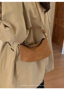 Detail of brown suede bucket bag with adjustable strap and gold brand lettering