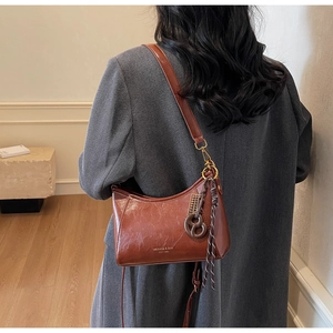 Detailed shot of brown wax leather crossbody bag with braided tassel and gold hardware