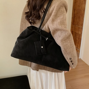 Detail of black suede tote bag featuring a small hanging purse and silver hardware