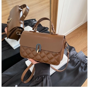 Detail of vintage brown quilted handbag with oval black-gold buckle and leather strap