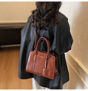 Detailed view of vintage brown leather handbag with gold lettering on a model