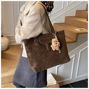 Detail of vintage brown tote bag with white contrast stitching and plush bear charm