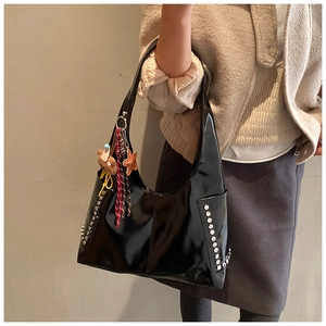 Détail du sac en cuir verni noir brillant avec des rivets argentés et des breloques