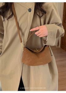 Close-up of brown crescent leather bag featuring golden twist lock and slim shoulder strap