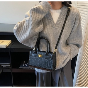 Detail of black crocodile texture bag with gold metal twist lock and leather handles