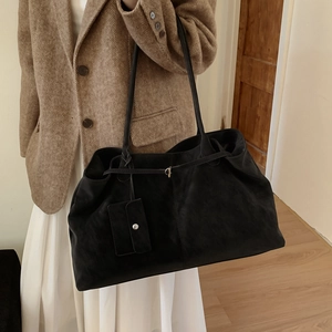 Macro shot of minimalist black suede tote bag detail with detachable mini pouch