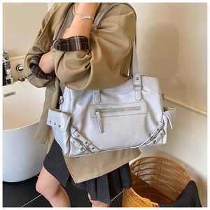 Detail of light blue-grey faux leather tote bag with rivets and multiple zip pockets
