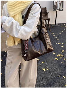 Détail du sac hobo en cuir verni marron foncé avec rivets argentés et ruban à pois