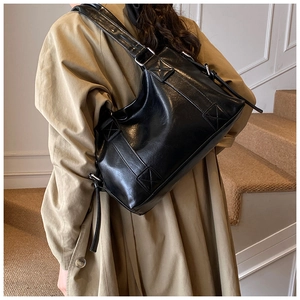 Detailed view of the black leather tote bag with unique square stitching and silver buckles
