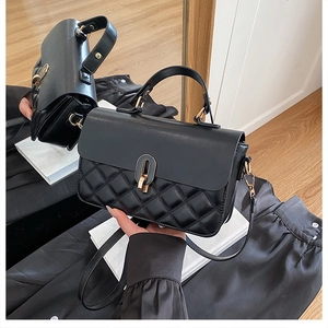 Detailed view of black quilted PU leather handbag with gold metal clasp and top handle