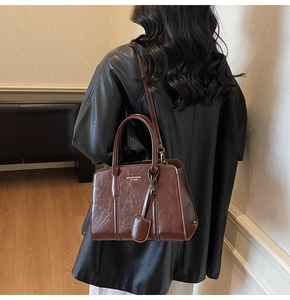 Detail of dark brown leather tote bag with round handles and adjustable shoulder strap