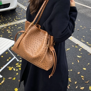 Close-up of brown ostrich texture tote bag with drawstring detail and slim straps
