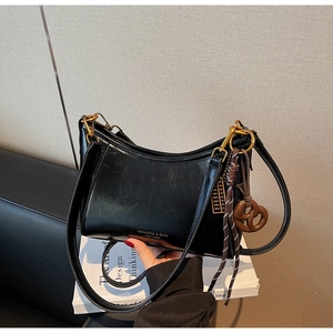 Detail of black wax leather hobo bag with gold hardware and creative abacus pendant