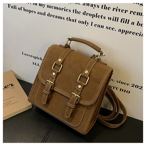 Detail shot of vintage brown leather backpack showing white stitching and gold buckles