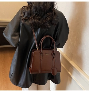 Detail of a dark brown glossy leather tote bag showing high-quality texture and branding