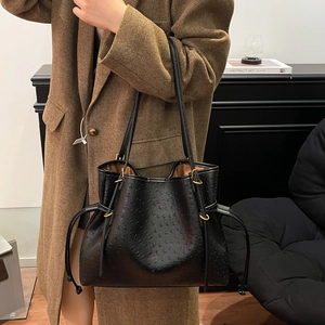 Detail of black ostrich embossed leather bucket bag paired with wool blazer for office style