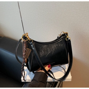 Close-up of black waxed leather shoulder bag with gold hardware and tassel detail