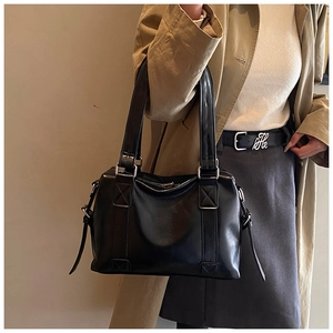 Detail view of large black PU leather tote bag with silver hardware and long shoulder strap